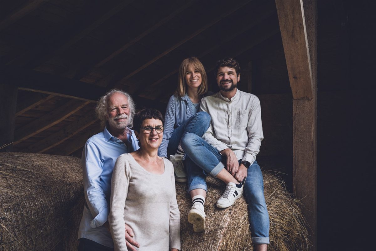 Rolf, Monika, Franziska und Manuel Siedler sitzen lachend auf Heuballen in der Scheune