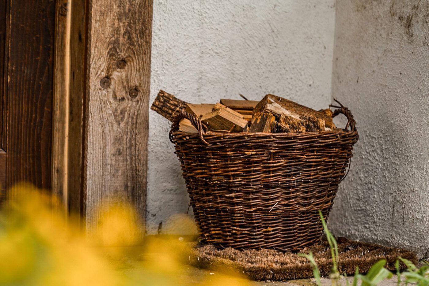 Weidenkorb mit Brennholz an der Hauswand